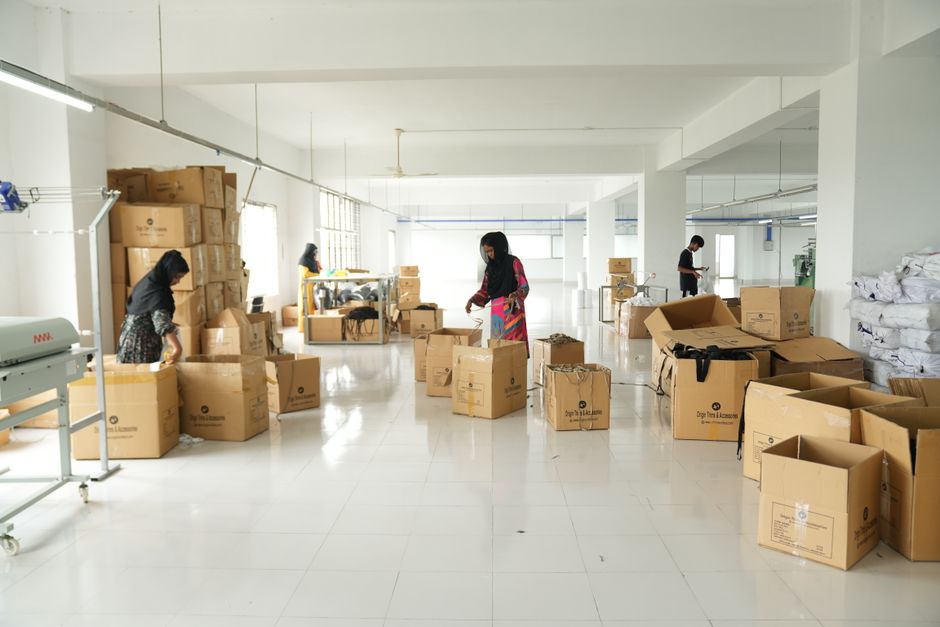 Workers in a spacious warehouse arrange and sort cardboard boxes with focused effort.